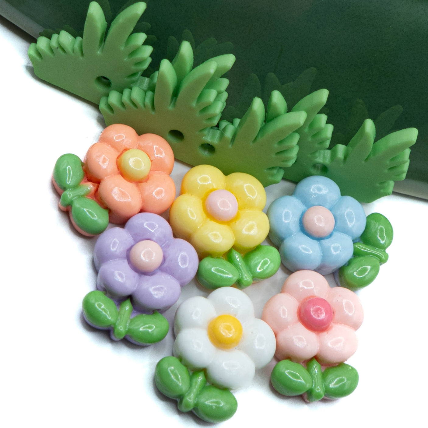 pastel resin flatback embellishments and grass buttons on white and green background
