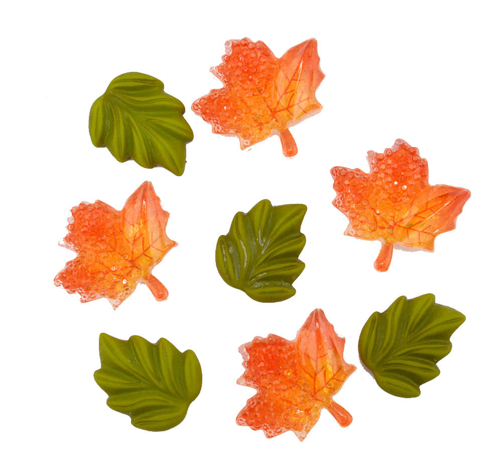 Seven small decorative leaf-shaped embellishments on a plain white background, including four orange maple leaves and three green oak leaves with a glittery finish.