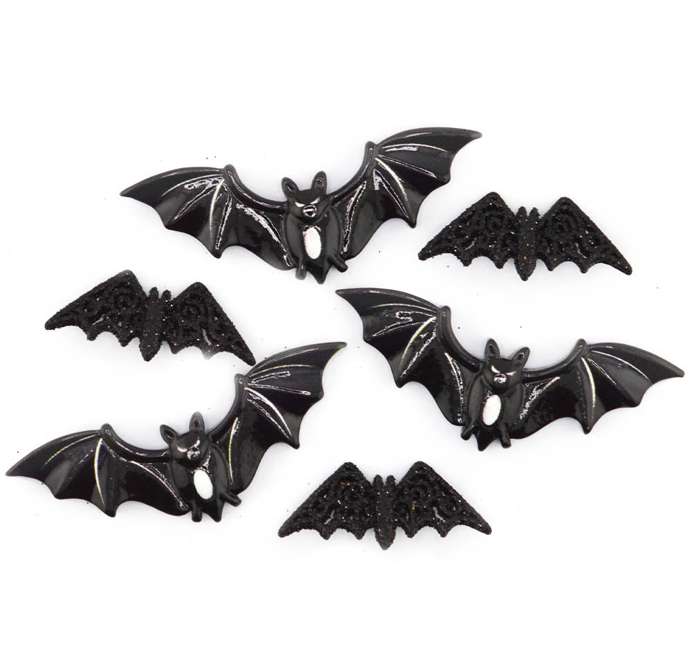 Five black bat-shaped jewelry findings or charms with glittery textured wings, arranged on a plain white background.