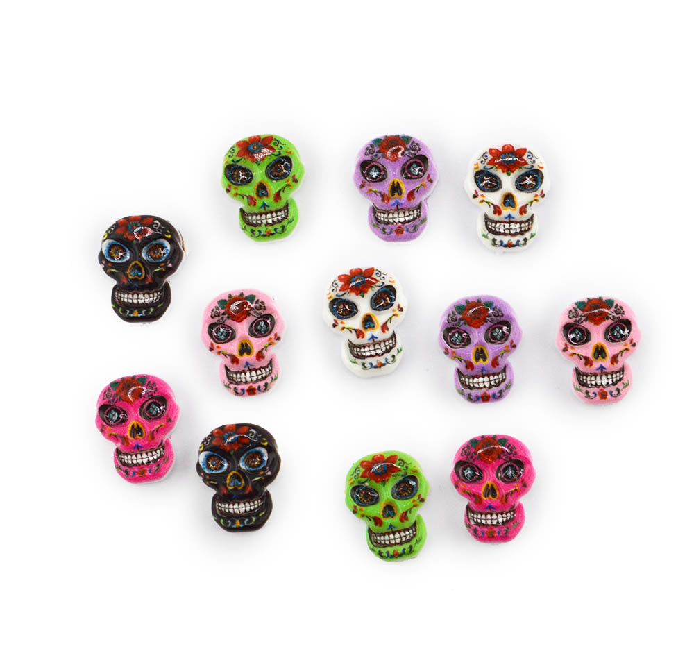 Ten colorful sugar skull beads arranged on a plain white background, featuring various designs in pink, green, purple, black, and white with red and orange decorative details.