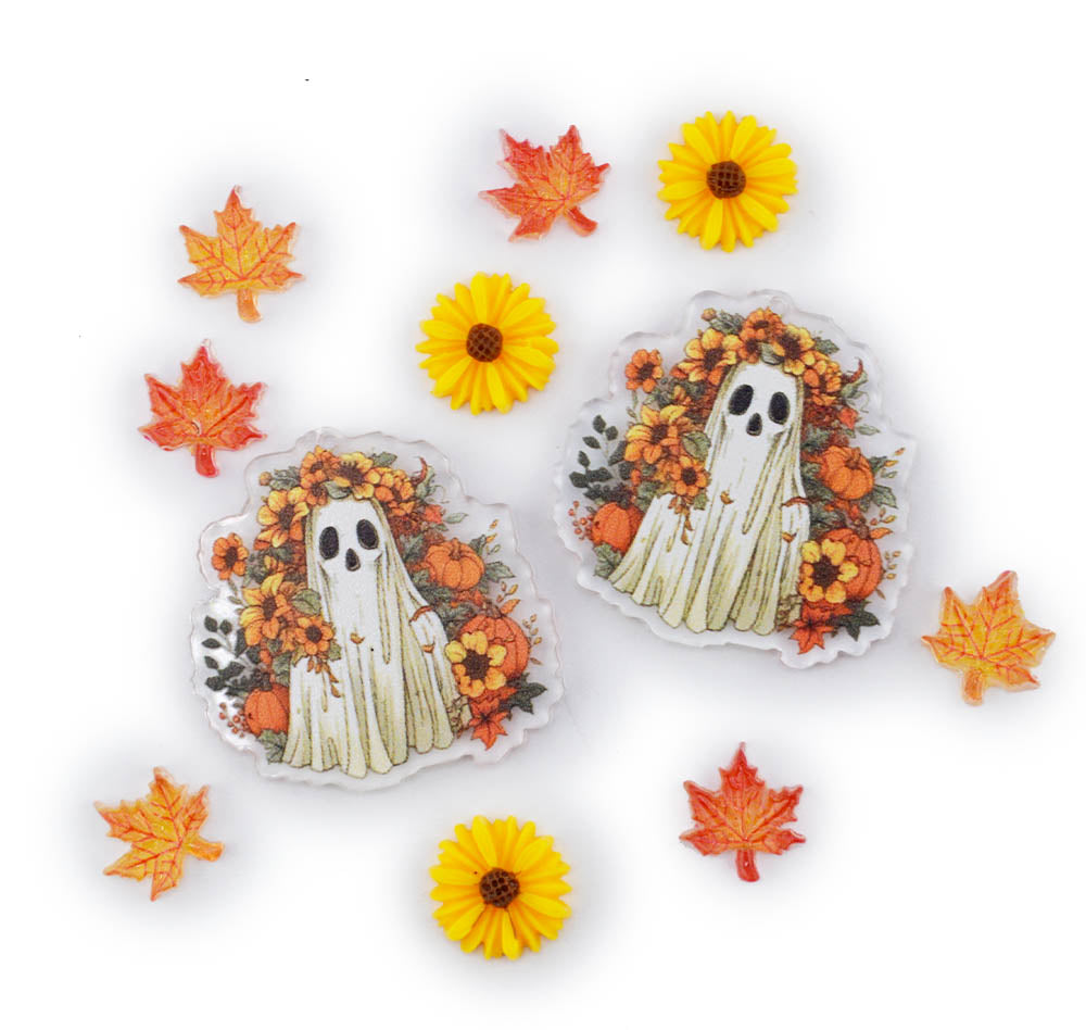 Two acrylic charms featuring a cute cartoon ghost surrounded by autumn flowers, leaves, and pumpkins, displayed on a white background with decorative autumn props.
