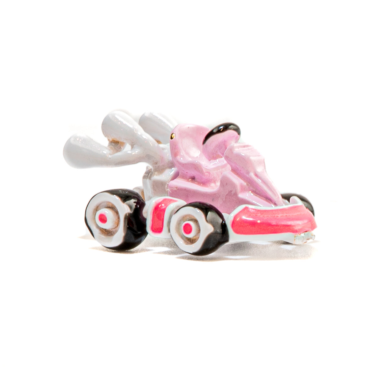 A small glossy pink and white go-kart figurine with black wheels, shown on a plain white background.