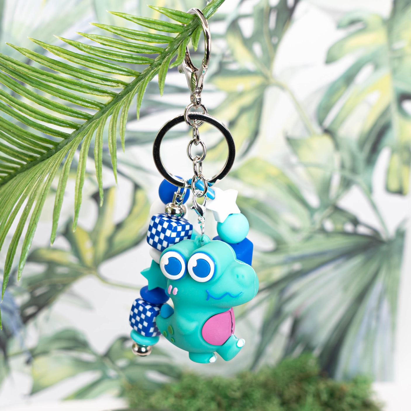 This fun DIY set includes a beadable keychain base, a large teal silicone dinosaur, and a mix of round, square, and shaped matching silicone beads