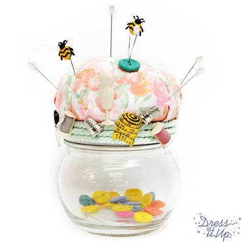 Sewing embellishments and cute bees are used to dress up a pin cushion