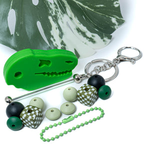 Add some prehistoric fun to your bags, purses, or backpacks with this Dinosaur-Shaped Silicone DIY keychain set