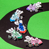 Five miniature toy race cars in assorted colors (white, blue, green, pink, purple) racing on a black curved track over a bright green background.