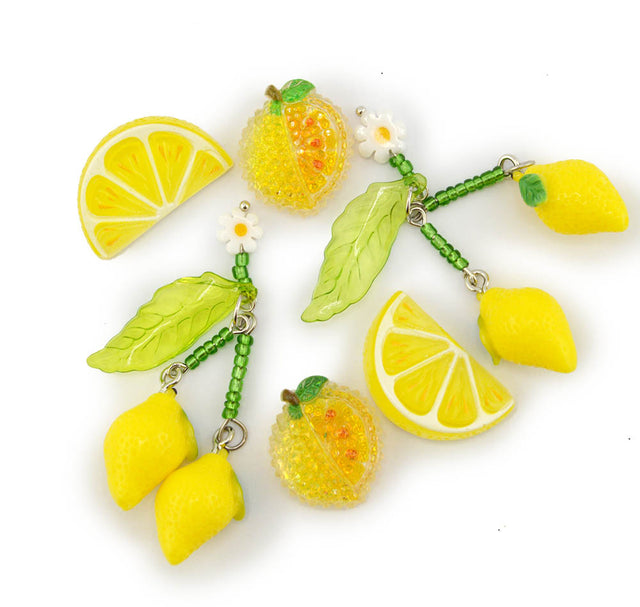 Two lemon-themed beaded jewelry charms on a white background, featuring yellow lemons, green leaves, green beads, and small white daisy flowers.