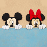 cartoon Mickey Mouse and Minnie Mouse peeking over a blue surface against a beige textured background.
