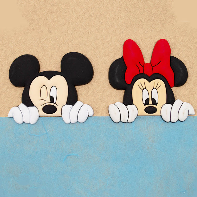 cartoon Mickey Mouse and Minnie Mouse peeking over a blue surface against a beige textured background.