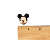 A small Mickey Mouse head charm or pin shown above a wooden ruler on a plain white background, likely indicating size.