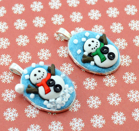 Two snowman-themed pendants on a pink background with white snowflake pattern