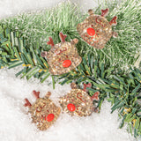 Decorative reindeer resin embellishments on a Christmas tree branch with snow background