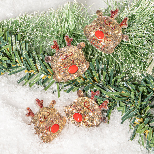 Decorative reindeer resin embellishments on a Christmas tree branch with snow background