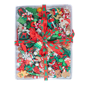 Assorted Christmas-themed decorative items in a clear container with a red ribbon.