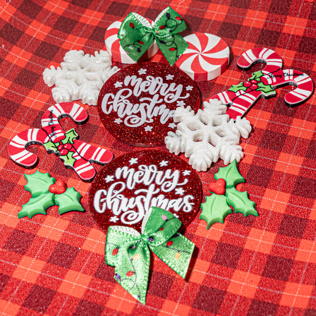 Collection of Christmas-themed embellishments including candy canes, holly leaves, and 'Merry Christmas' ornaments on a red plaid background