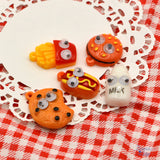 Quirky food with googly eyes. Hamburger, fries, hot dog, cookie and bottle of milk