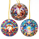 Three round Christmas ornaments with colorful stained-glass-style Nativity scenes, hanging from gold strings against a plain white background.