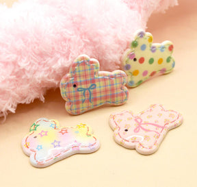 Flat plastic bunny shapes embellishments on a pink background