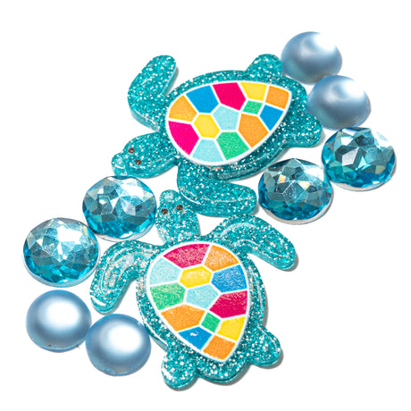 Two glittery turtle embellishments with colorful shell designs on a white background.