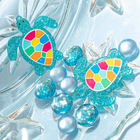 Colorful turtle-shaped embellishments with rhinestone on a blue background